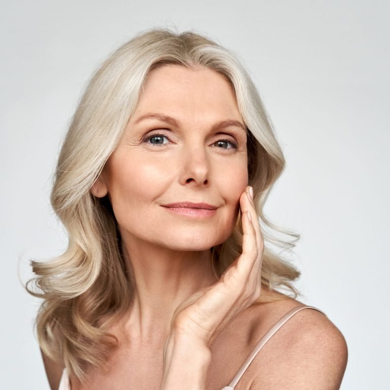 Beautiful gorgeous 50s mid aged mature woman looking at camera isolated on white. Mature old lady close up portrait. Healthy face skin care beauty, middle age skincare cosmetics, cosmetology concept